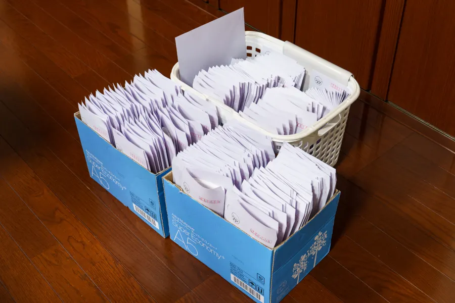 発送を待つ封筒がぎっしり詰まった箱とかご